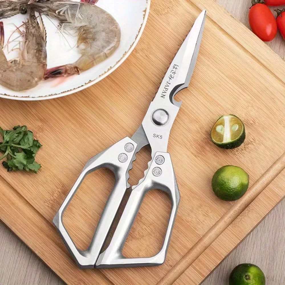 The shears closed on a bamboo board beside limes and prawns, bottle-opener cut-out and handle teeth visible